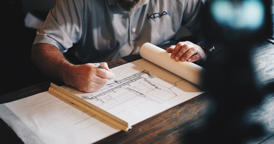 Un architecte travaille sur un plan, crayon et règle en main