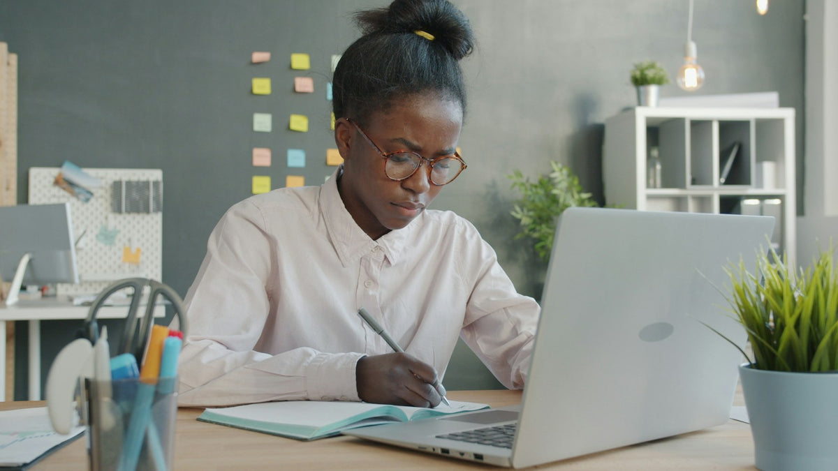 Une femme prend des notes à son bureau
