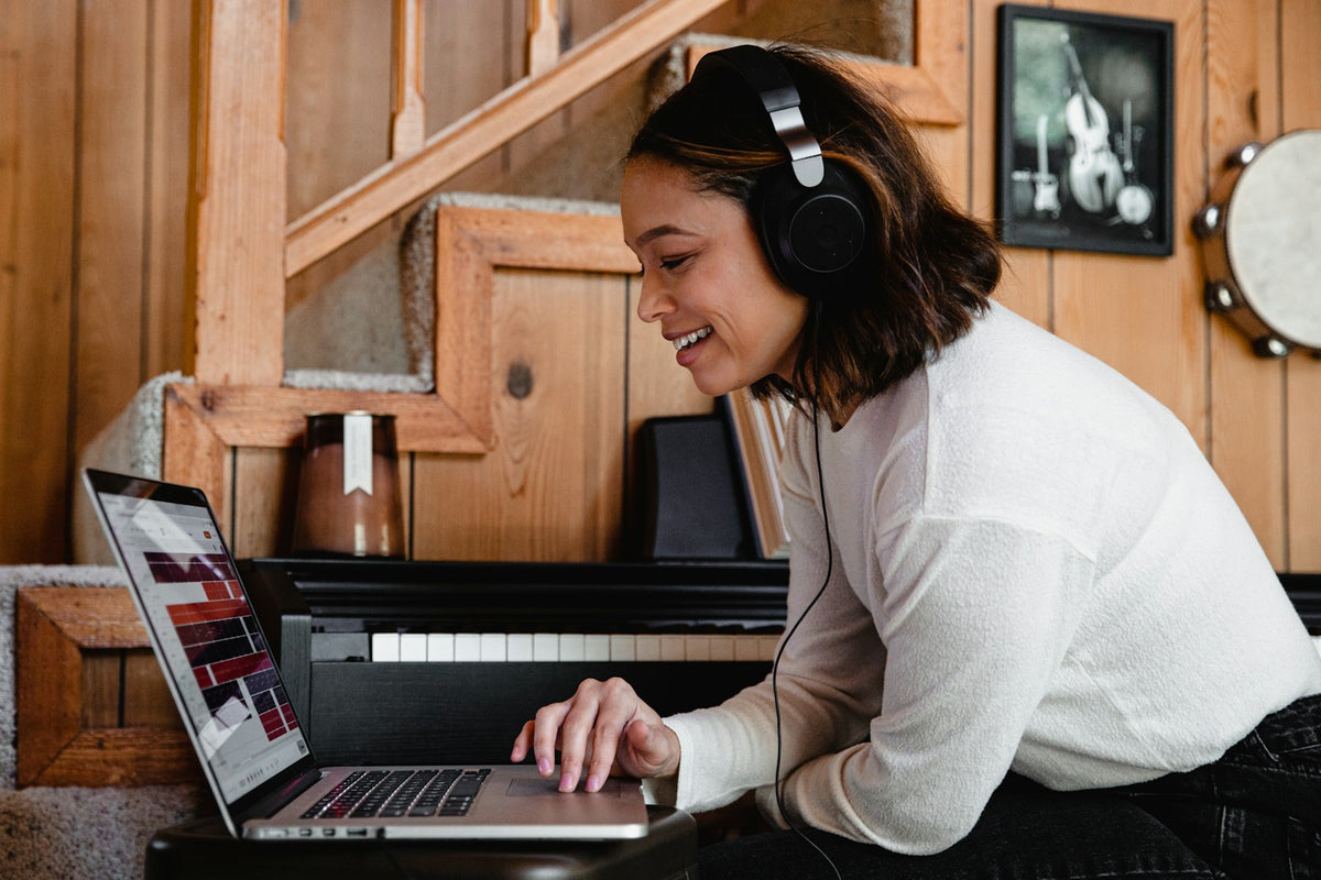 Une femme avec un casque sourit devant son ordinateur portable